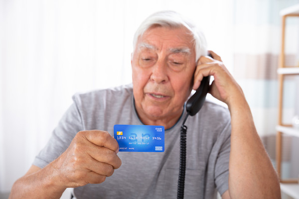 Close-up Of A Senior Man With Credit Card Using Landline Phone